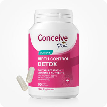 Conceive Plus Birth Control Detox bottle featuring a bright pink and white label with bold text, shown upright on a white background with two translucent vegan capsules lying diagonally at base of container.