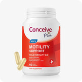 Conceive Plus Men's Motility Support bottle featuring a bold red and white label with clear text highlighting male fertility aid benefits, shown upright with two beige vegan capsules placed beside it on a light grey background.