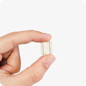 Conceive Plus Men's Motility Support capsules shown close-up between fingers, highlighting vegan capsule size and texture against a soft white background, ideal for visualizing daily dosage.